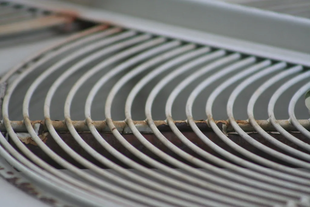 Close-up of the curved metal fan guard on top of an outdoor air conditioning unit