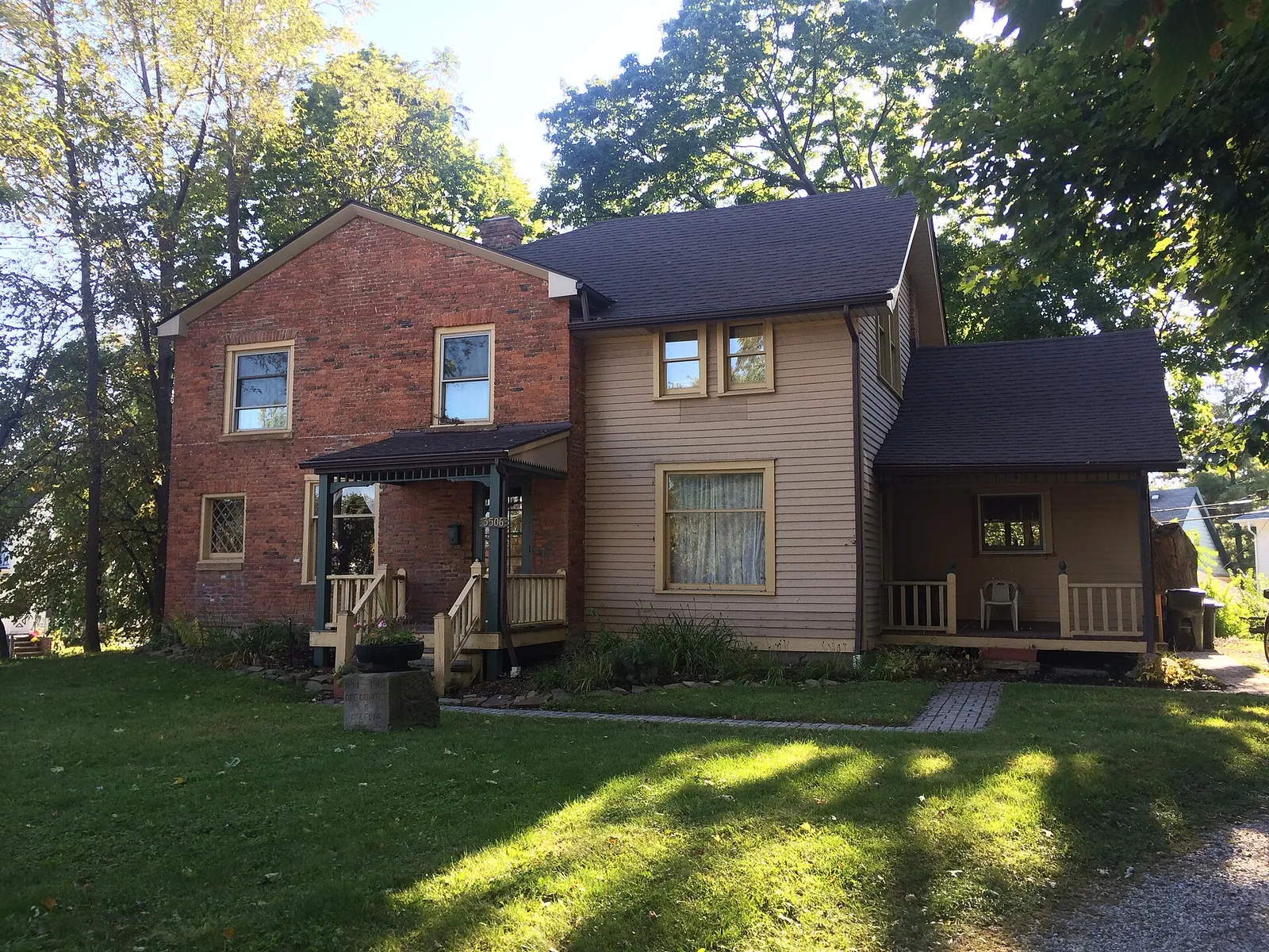 Historic Jeremiah Gates home in Old Brooklyn, a brick and tan-sided house with a front porch on a sunny green lawn
